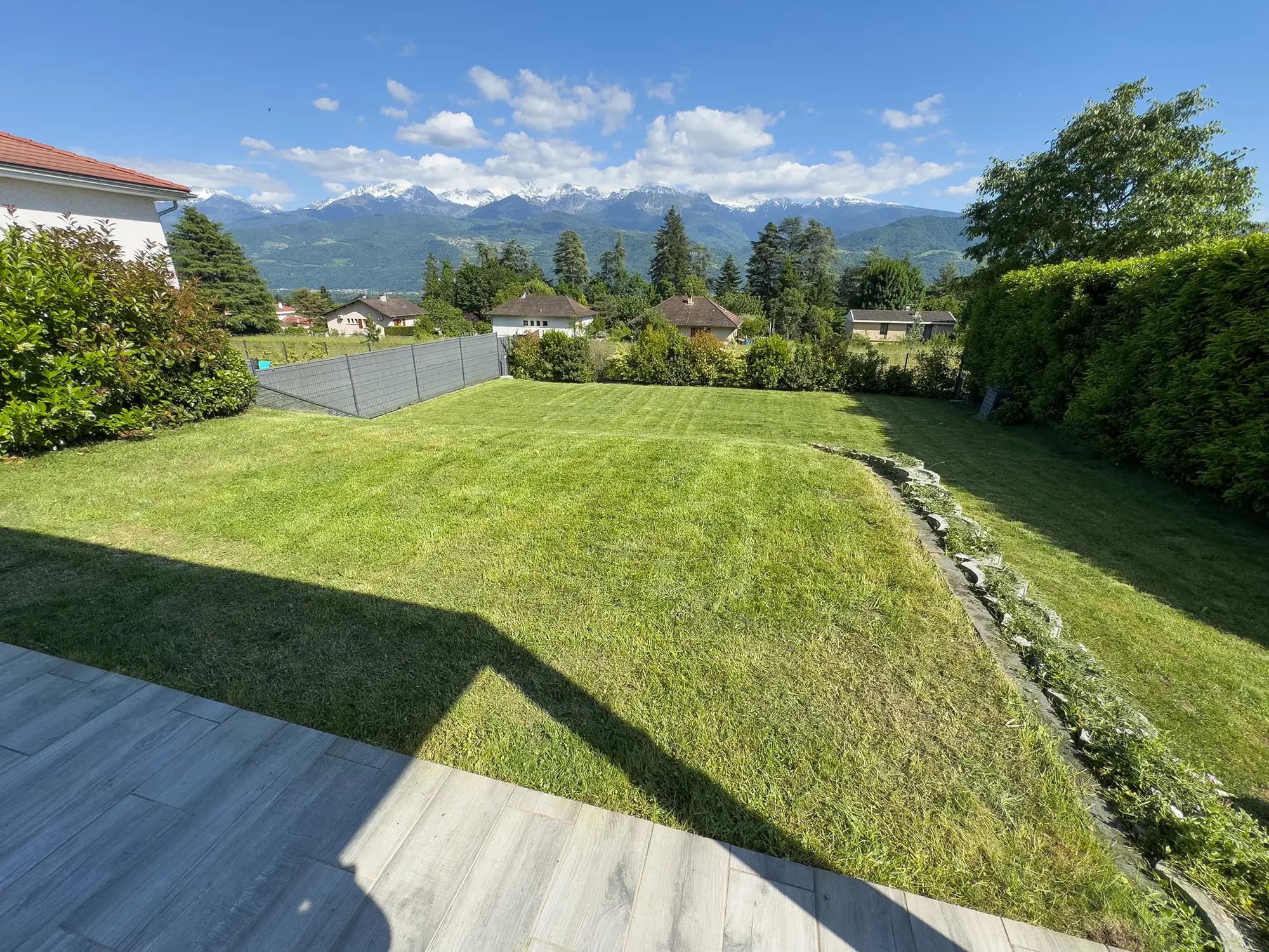 Vue d’ensemble d’un jardin avec gazon, terrasse et haies